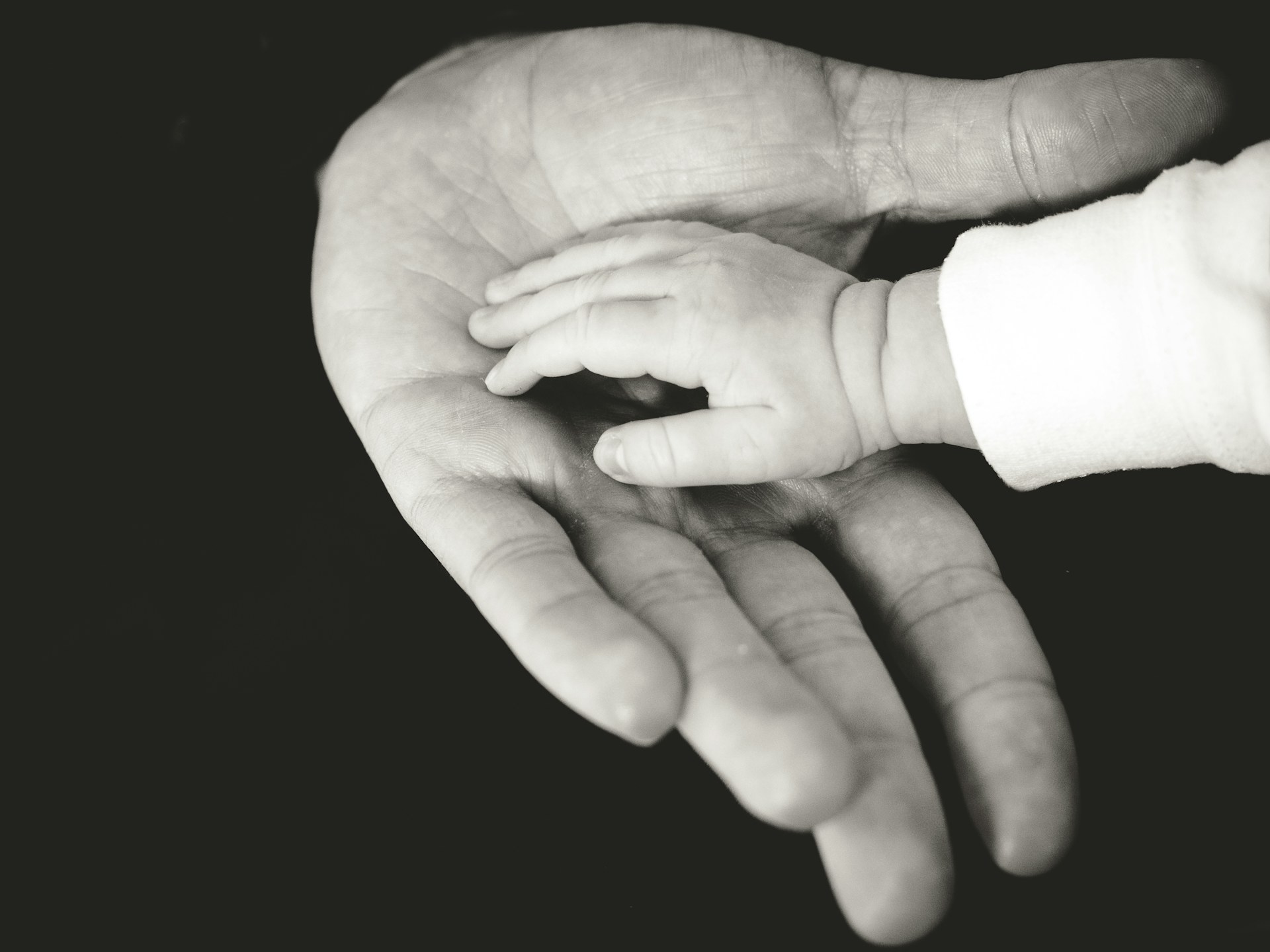 Mano di un bambino appoggiata al palmo di un adulto
